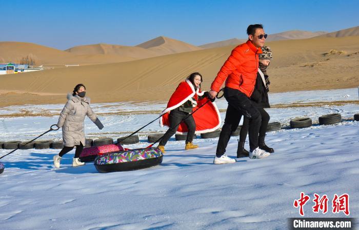 圖為游客和市民在鳴沙山下享受大漠冰雪帶來的歡樂?！⊥醣筱y 攝