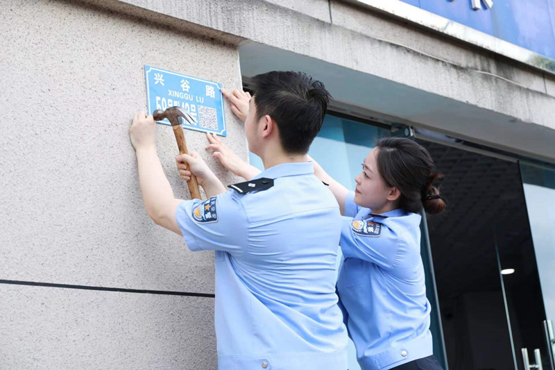 民警在興谷路裝訂二維碼門樓牌。重慶高新區(qū)公安分局供圖
